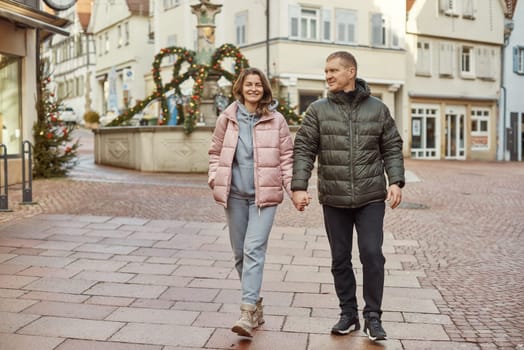 Loving couple of tourists walking around old town. Man woman couple walking europe old town Germany. Couple of lovers leisurely stroll in the cool autumn morning on the streets of a BIETIGHEIM-BISSINGEN (Germany). The guy holds his wife. Vacation, autumn, holiday. Couple Walking in Europe's Old Town