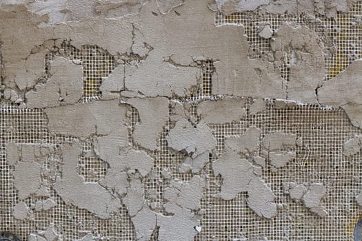 cheap plaster peeled off, revealing mesh layer - full-frame background and texture