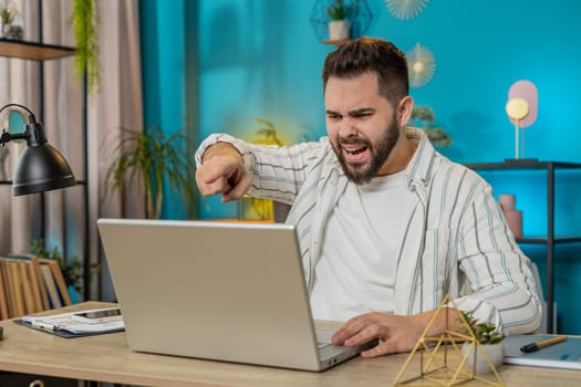 Nervous angry manager quarrelling laptop call online at home office Emotional businessman talking aggressively computer video call. Stressed freelancer scolding subordinates during webinar. Lifestyle