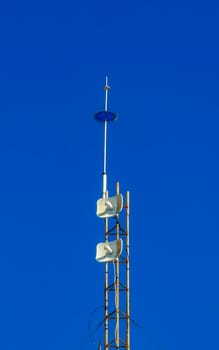 Red white 5G tower with blue sky background radiation kills us in Zicatela Puerto Escondido Oaxaca Mexico.