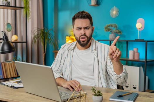 Displeased upset Caucasian man reacting to unpleasant awful idea, dissatisfied with bad quality, wave hand, shake finger No, dismiss idea don't like proposal. Young guy at home office table. Lifestyle