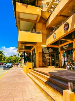 Typical beautiful colorful tourist street road and sidewalk with city life cars traffic buildings hotels bars restaurants and people in Zicatela Mexico.