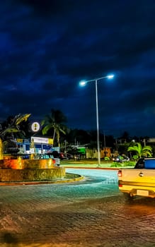 Busy road street driving cars vehicles traffic jam and traffic circle roundabout with dolphin dolphins sculpture statue with fountain at night in Zicatela Puerto Escondido Oaxaca Mexico.