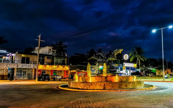 Busy road street driving cars vehicles traffic jam and traffic circle roundabout with dolphin dolphins sculpture statue with fountain at night in Zicatela Puerto Escondido Oaxaca Mexico.