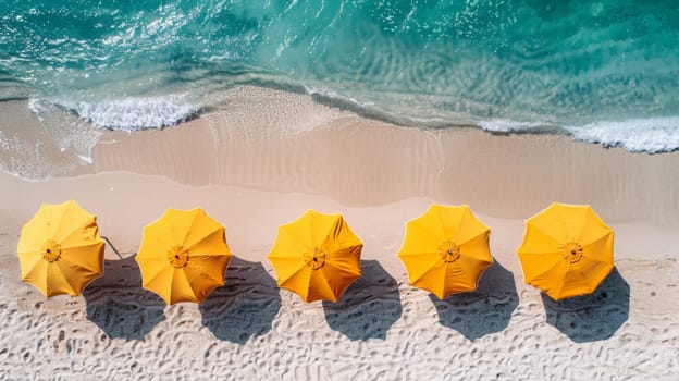 A row of yellow umbrellas on the beach next to a blue ocean