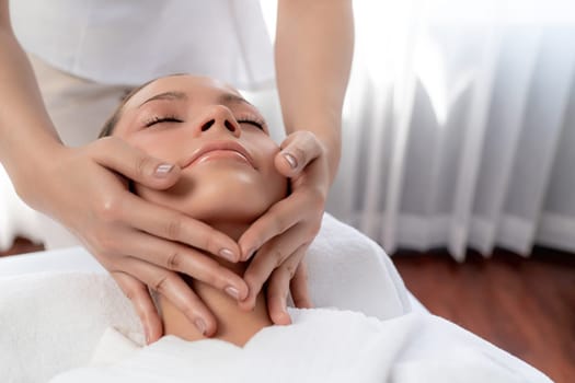 Caucasian woman enjoying relaxing anti-stress head massage and pampering facial beauty skin recreation leisure in dayspa modern light ambient at luxury resort or hotel spa salon. Quiescent