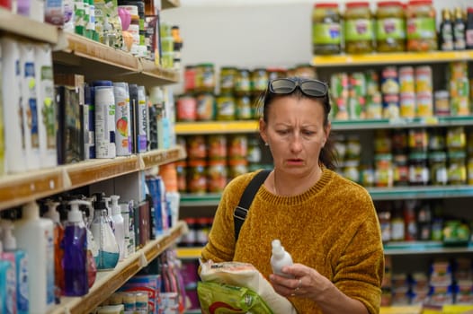 Portrait of a young woman choosing household chemicals in a supermarket 3