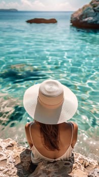 A woman in a white hat looking at the ocean from above