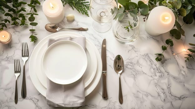 A white table setting with silverware, plates and candles