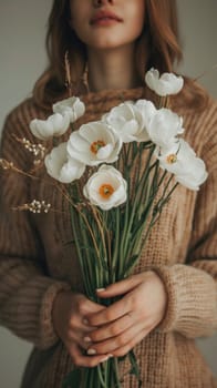 A woman in a sweater holding flowers and looking down