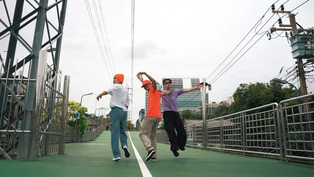 Back view of skilled hipster walking while turn around and looking at camera. Group of professional break dancer pose at camera and perform street dance foot step. Outdoor sport 2024. Sprightly.