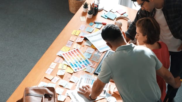 Top view of smart designer holding color palette while project manager looking at design and choosing color for program. Professional businesswoman taking a note while design creative logo. Symposium.