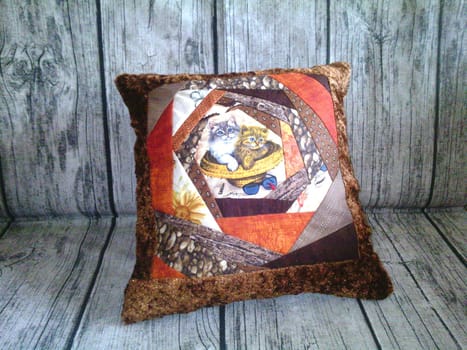 A decorative pillow is placed on a wooden surface, adding a touch of coziness and style to the room. The intricately designed pillow stands out against the rustic backdrop of the wooden table.