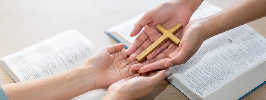 Close-up women prayer deliver holy bible book and holy cross to young believer. Spreading religion symbol. Concept of hope, religion, christianity and god blessing. Warm background. Burgeoning.