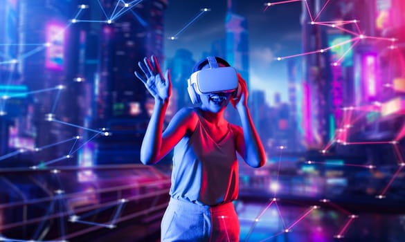 Female standing in virtual reality cyberpunk style building wear VR headset connecting metaverse, future cyberspace community technology, Woman dancing raising one arm holding goggle. Hallucination.