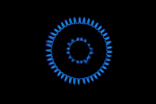 Gas burns blue on black background. Heat and Mirage above the gas hob switched on. Top view of a kitchen burner glowing at night, close-up. Natural gas concept. The gas stove is on.