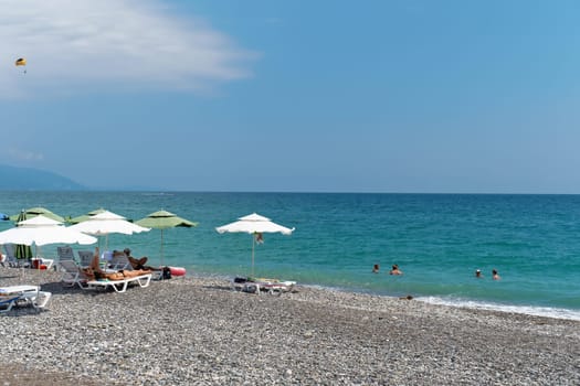 The azure sea, the beach, vacationers sunbathing on the shore. Abkhazia, the city of Gagra - August 18, 2023.