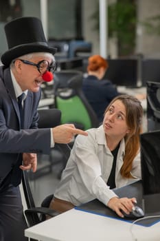 Caucasian woman communicates with an elderly man in a clown costume in the office. Vertical photo