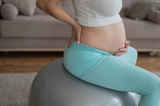 Caucasian pregnant woman suffers from belly pain. Fitball training during pregnancy