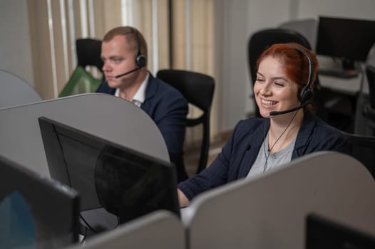 Two friendly call center employees answer customers by phone. Man and woman woman talking on a headset in the office