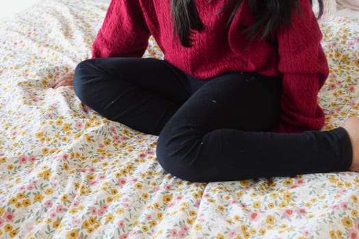 child sitting W posture on the bed .