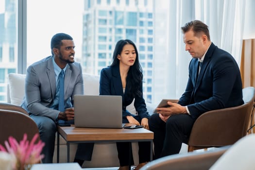 Smart caucasian businessman present marketing idea by using tablet. Group of business team listening while deciding to invest in start up project at modern lounge. Ornamented.