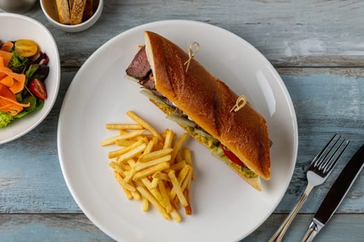 Grilled steak sandwich with french fries on a white porcelain plate