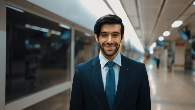 Portrait of professional business man smile at camera while standing at train station. Caucasian executive manager looking at camera while standing with confident with blurred background. Exultant.