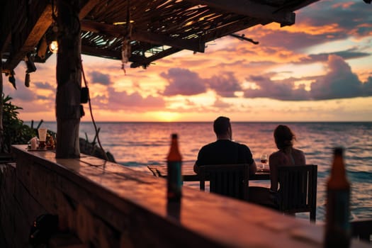A couple drinks wine in a cafe against the backdrop of a sunset at sea. Silhouettes of people.