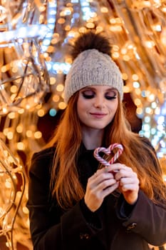 Christmas mood. Woman with long hair in sity decorated for Christmas. She is dressed in a black coat