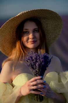 Lavender sunset girl. A laughing girl in a blue dress with flowing hair in a hat walks through a lilac field, holds a bouquet of lavender in her hands