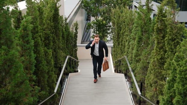 Caucasian businessman walking up stair and calling manager by using smart phone. Top view of manager talking marketing team and planning financial strategy by telephone while going up stair. Urbane.