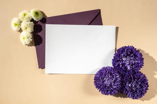 Beautiful little violet flowers on postal blue envelope on beige background, empty paper note copy space for text, spring time, greeting card for holiday. Flower delivery concept