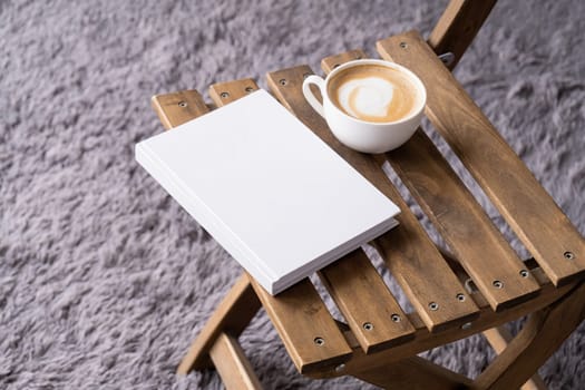 blank book mockup on wooden chair with cappuccino, pen and grey rug. Template book cover