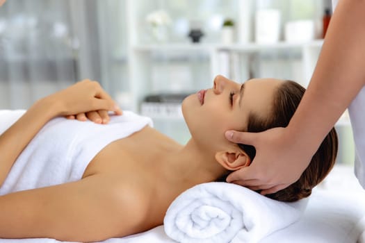 Caucasian woman enjoying relaxing anti-stress head massage and pampering facial beauty skin recreation leisure in dayspa modern light ambient at luxury resort or hotel spa salon. Quiescent