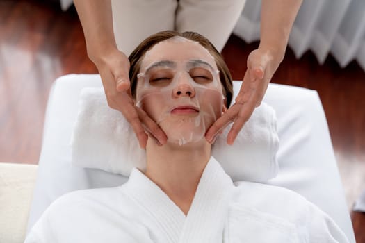 Serene modern daylight ambiance of spa salon, woman customer indulges in rejuvenating with facial skincare mask. Facial skin treatment and beauty cosmetology procedure for face. Quiescent