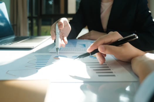 Two people are looking at a table with graphs and a pen. They are discussing the data on the graphs