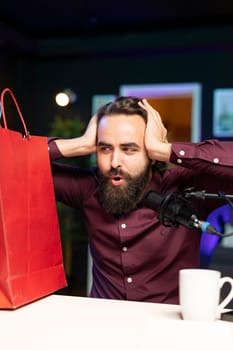 Media star impressed by unbelieving shopping haul products, showing fans purchases he recently got. Content creator in studio doing shocked gesturing, surprised by acquisitions