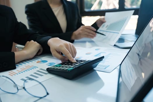 A woman is using a calculator to add numbers on a table with other people. Concept of focus and concentration as the woman works on her calculations