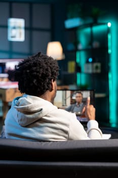 African american job candidate remotely being interviewed via internet videocall by manager. Man answering HR person interview questions during videoconference meeting while staying in apartment