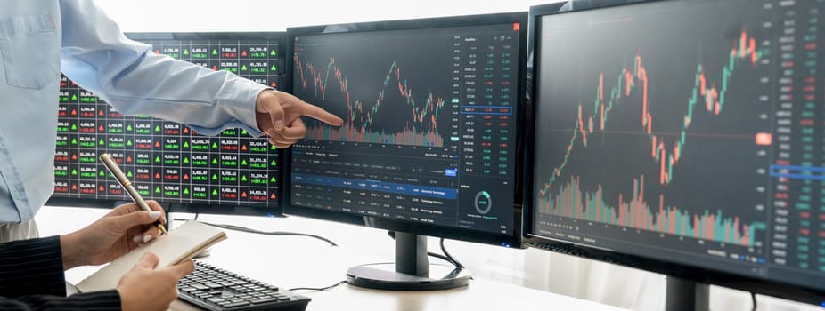 A cropped close-up image of professional smart trader hand pointing at financial growth graph while write data analysis in notebook. Business finance and Stock market investment concept. Burgeoning.