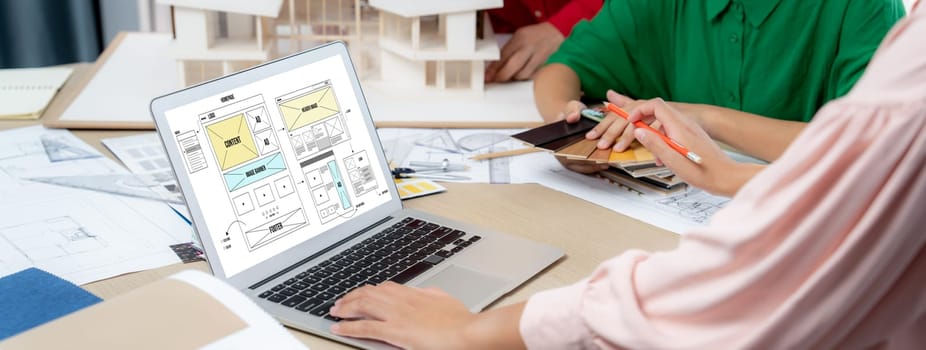 Cropped image of interior designer team discuss the material color while laptop displayed website wireframe designs for mobiles app and website. Creative design and business concept. Variegated.