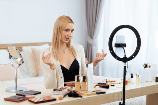 Young woman making beauty and cosmetic tutorial video content for social media. Beauty blogger smiles to camera while showing how to beauty care to audience or followers. Blithe