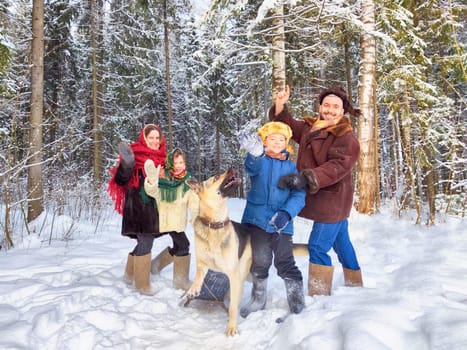 Joyful family ethnic dress with shawls and earflap hats and dog in winter forest in Russia carnival Maslenitsa. Tourists in Shrovetide in spring. Mother, father, son, daughter having fun in snow