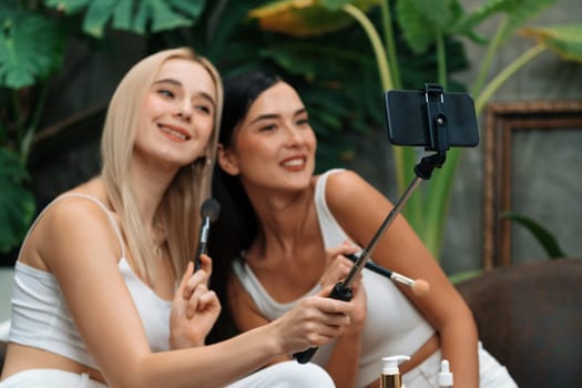 Two beautiful content creator making natural beauty and cosmetic tutorial on green plant garden video. Beauty blogger showing how to beauty care to social medial audience using selfie stick . Blithe