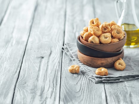 Traditional italian snack taralli or tarallini in wooden bowl over old gray wooden table. Rustic shot of taralli appetizer with copy space