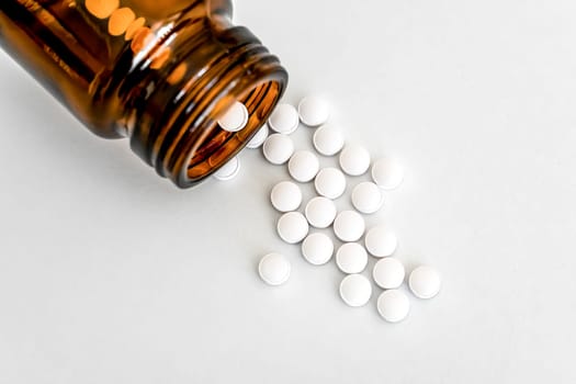 Tablets Close-Up, White Pills and Brown Glass Vial Arranged on Table, Flatlay, Copy Space, Close-Up, Concept of Healthcare