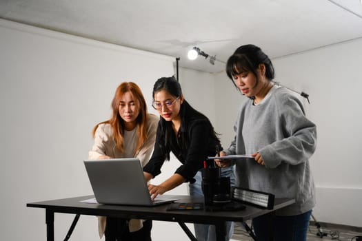 Young creative people using laptop working together in a professional studio.