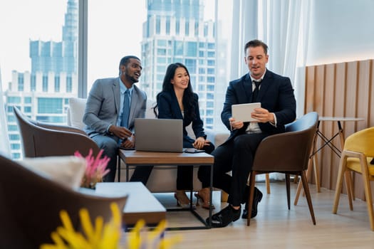 Smart caucasian businessman present marketing idea by using tablet. Group of business team listening while deciding to invest in start up project at modern lounge. Ornamented.