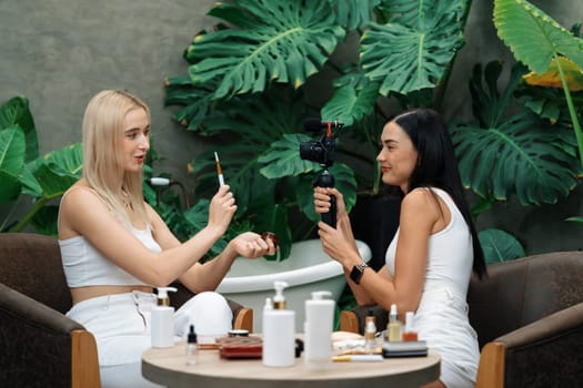 Two beautiful content creator making natural beauty and cosmetic tutorial on green plant garden video. Beauty blogger showing how to beauty care to social medial audience using selfie stick . Blithe